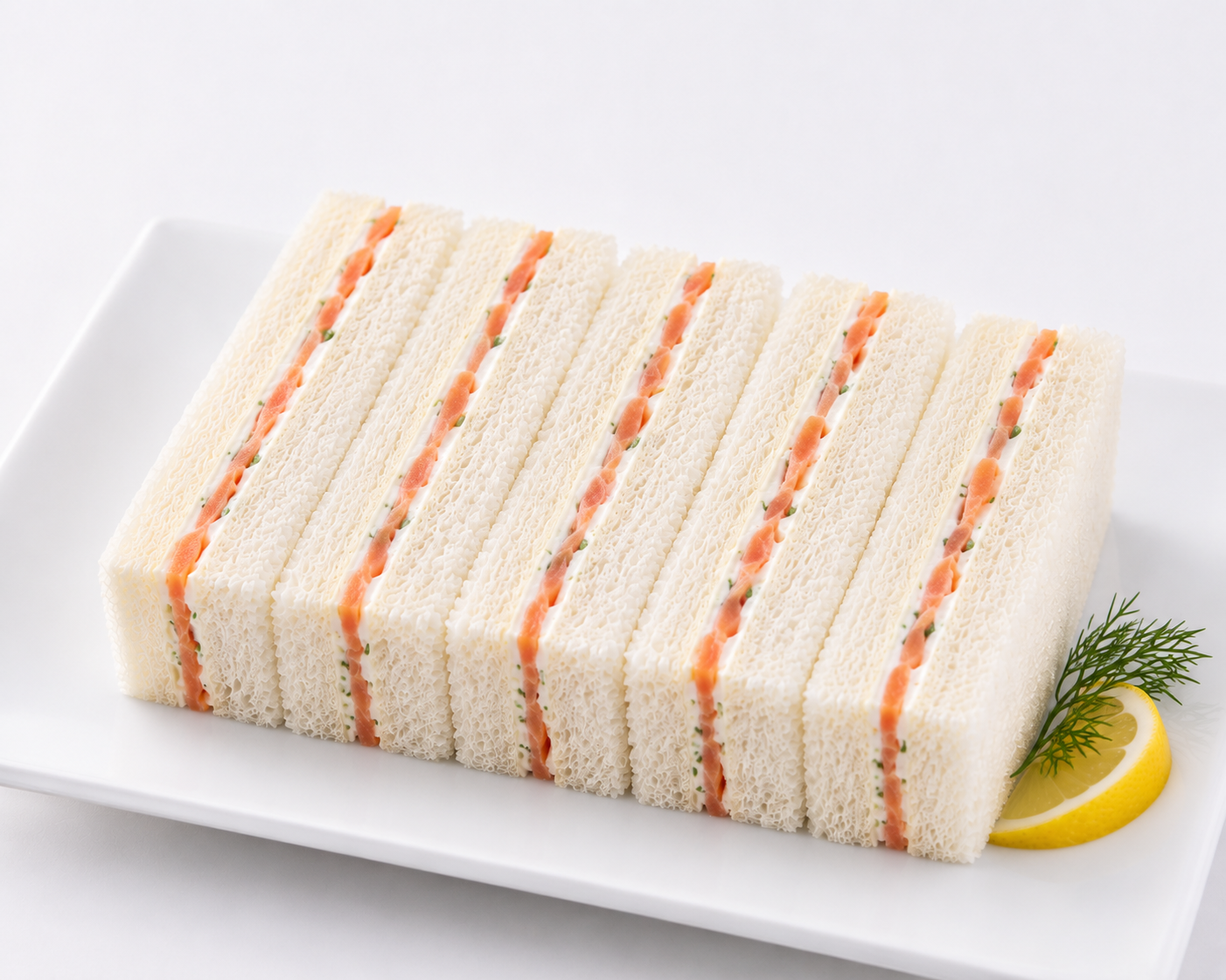Roll of sandwich slices with salmon on a white plate