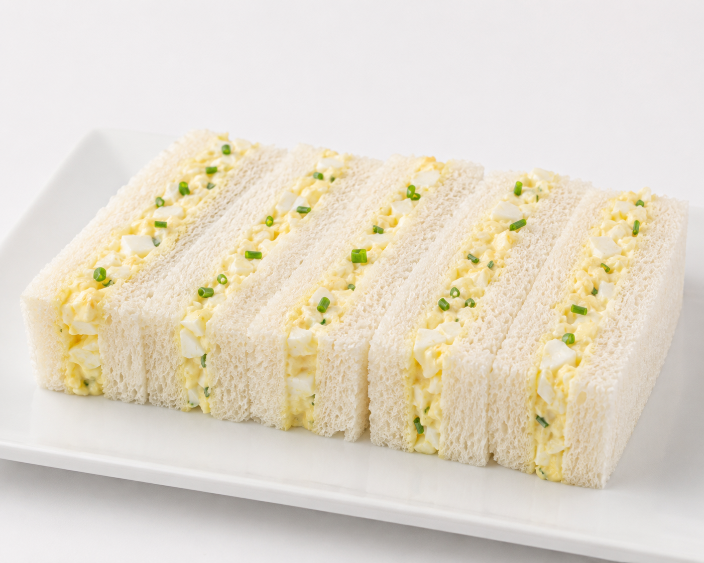 Rolled sandwich with egg and green onion on a white plate