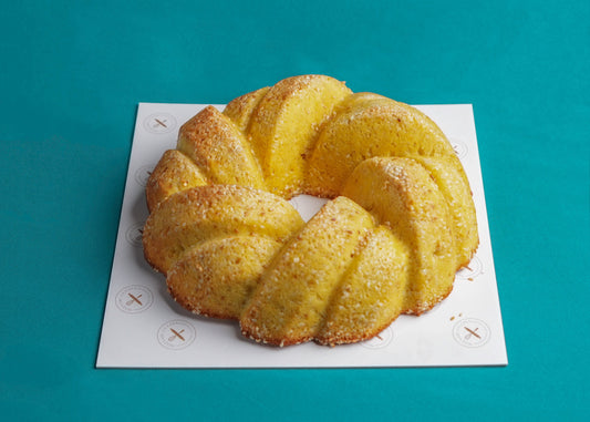 A golden-brown bundt cake on a white plate with a blue background.